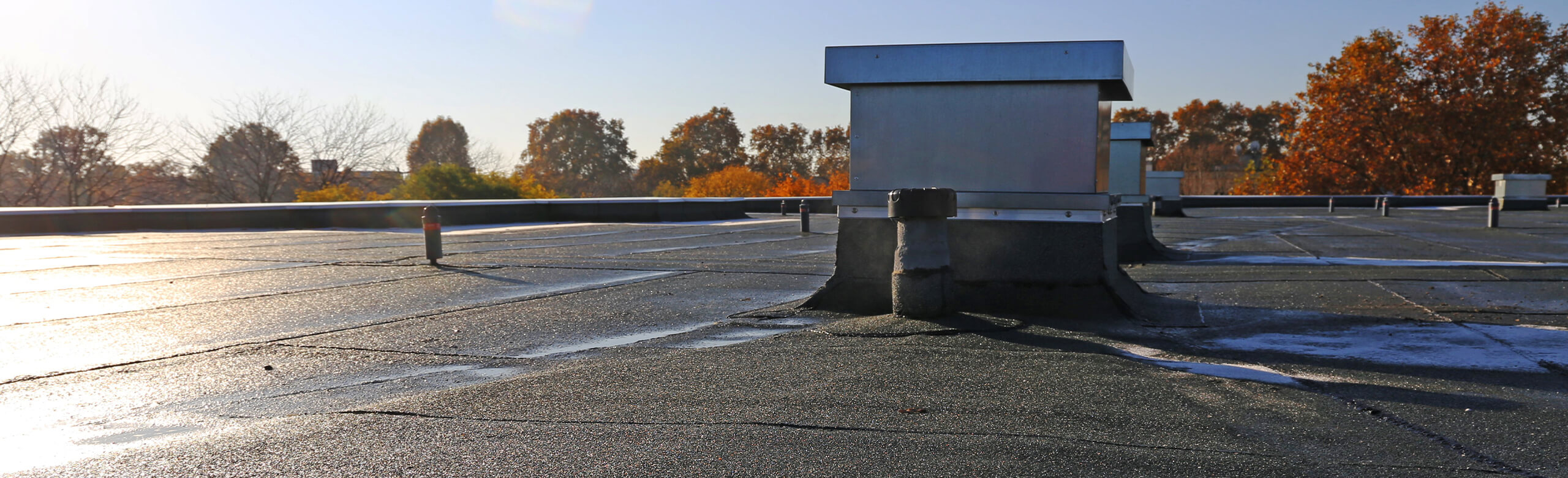 Construction – Flat Roof & Waterproofing Solutions Flat roof with rooftop units and sealed waterproofing details in autumn light